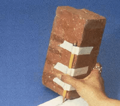 A hand trying to write with a pen tied to a brick